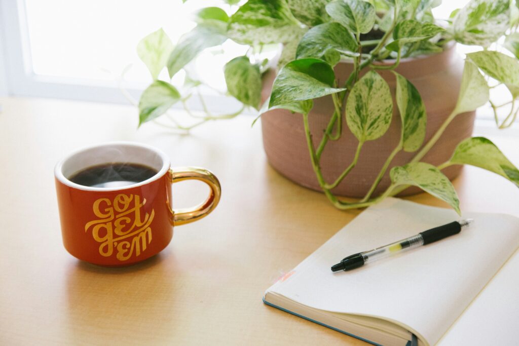 Un café junto a un cuaderno y un lápiz